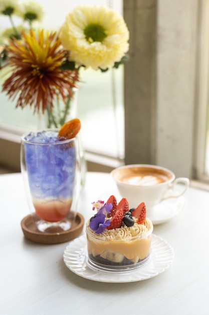 Una taza de café y un postre morado y azul sobre una mesa.