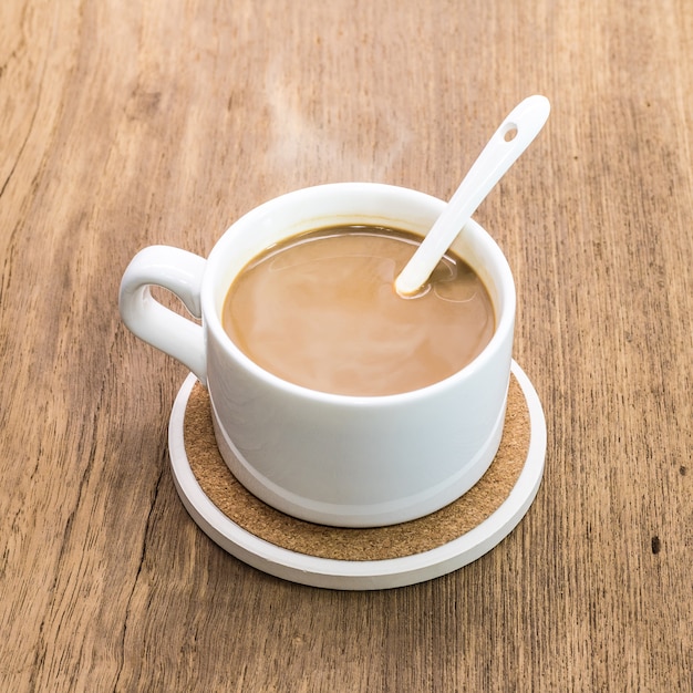 Taza de café y práctico de costa de la bebida en fondo de madera.