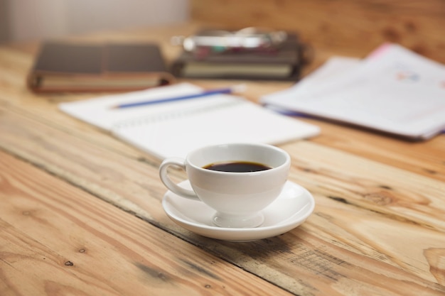 Taza de café del primer en el escritorio de oficina con el papel y la carta del análisis.