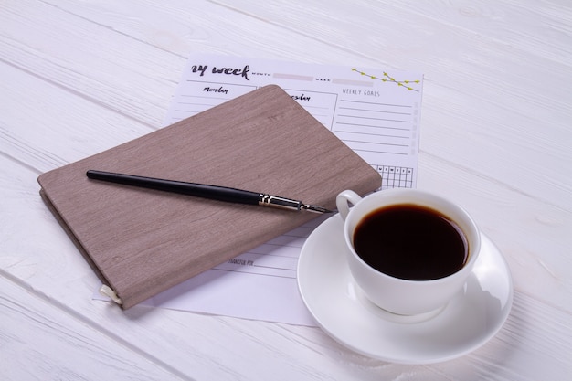 Foto taza de café de primer plano con bolígrafo de tinta y libro.