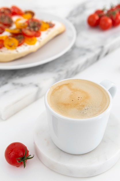 Foto taza de café de primer plano y sándwiches con queso crema y tomates