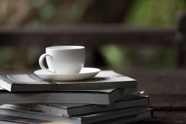 Taza de café puesta en la pila de libros en la mañana.