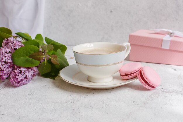 Taza de café, una rama de lilas y macarrones