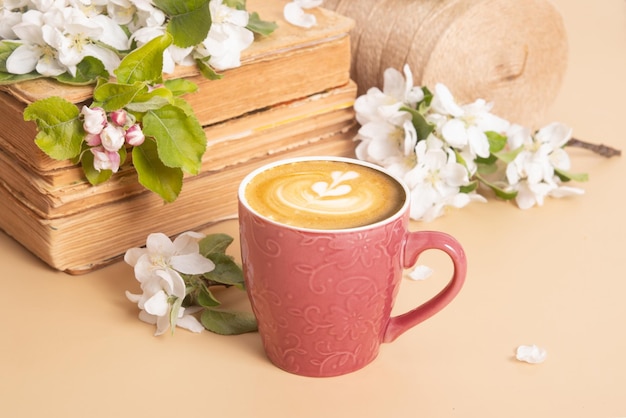 Taza de café y ramitas de manzana en flor con libros antiguos Composición de bodegones de primavera