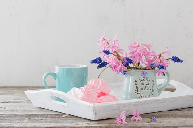 Una taza de café y un ramo de flores sobre una mesa de madera