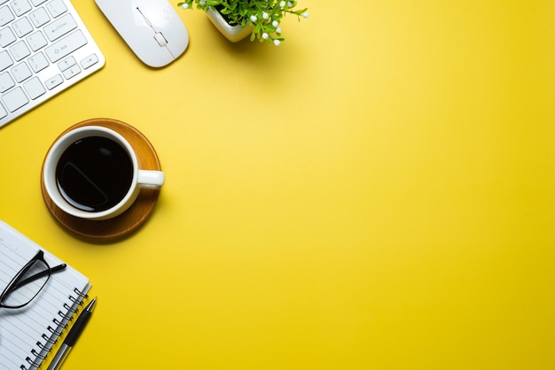 Taza de café con ratón de teclado portátil colocado sobre fondo amarillo. Copie el espacio.