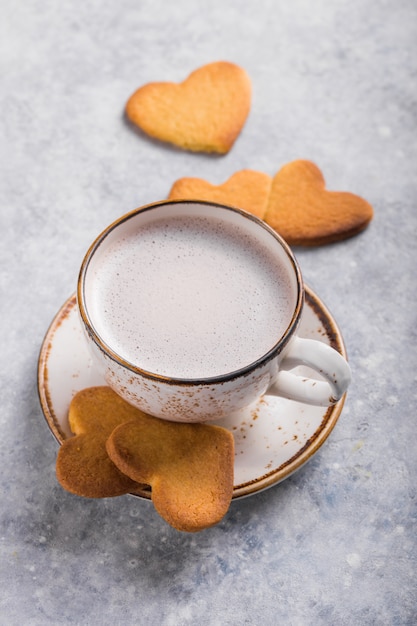 Taza de café recién hecho y galletas de corazón