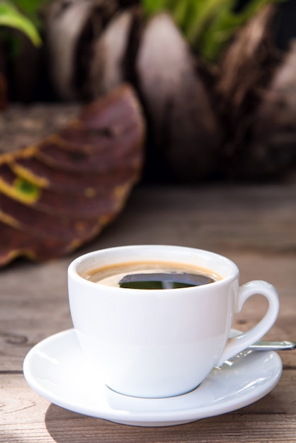 Taza de café recién hecho con granos de café en la mesa de madera