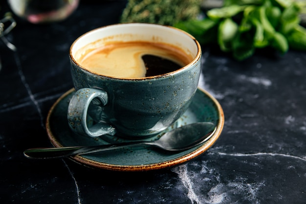 Taza de café recién hecho negro sobre la mesa de mármol oscuro