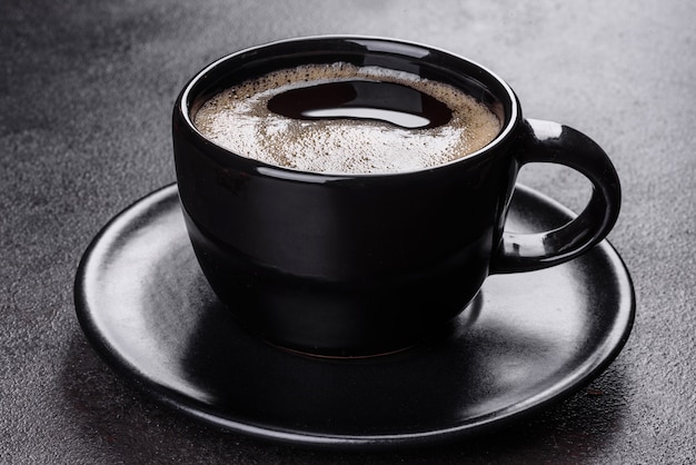 Una taza de café recién perfumado para un comienzo alegre del día. Hermosa taza de café con café en una mesa oscura