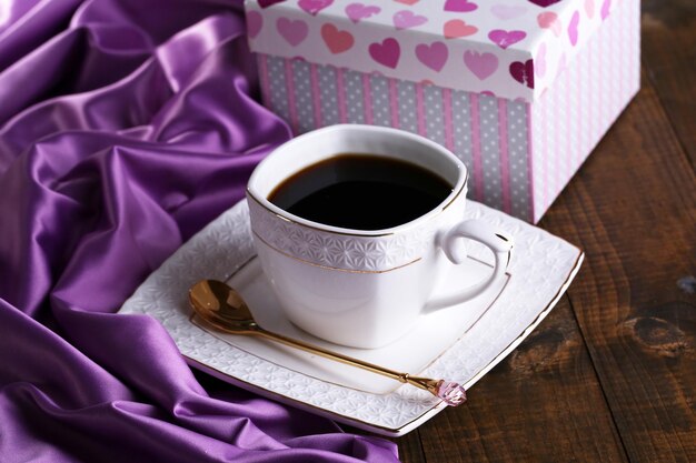 Taza de café y regalo en primer plano de la mesa de madera