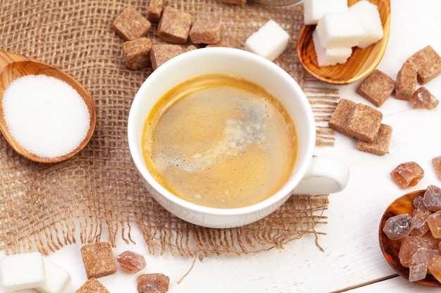 Taza de café con rodajas de azúcar en la mesa de madera