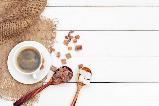 Taza de café con rodajas de azúcar en la mesa de madera