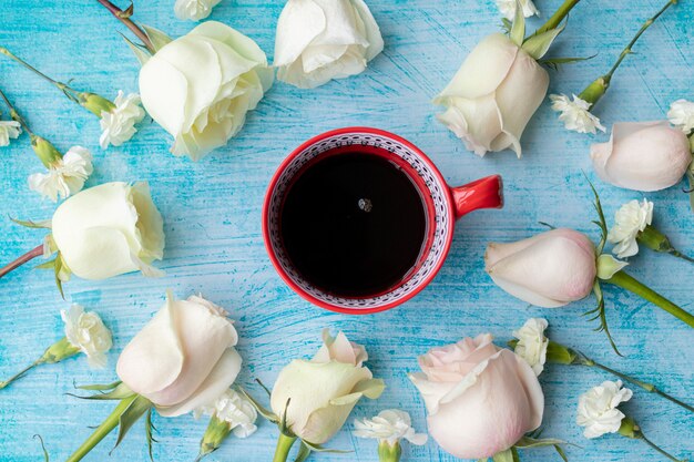 Taza de café rodeada de rosas blancas