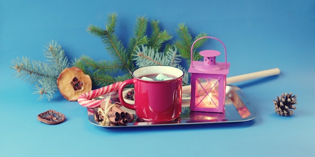 Taza de café roja de Navidad con merengue linterna con una vela encendida especias ramas de abeto