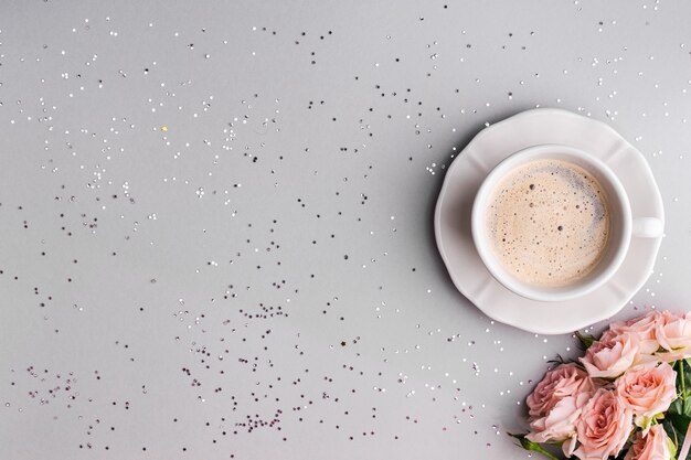 Taza de café con rosas rosadas sobre un gris festivo