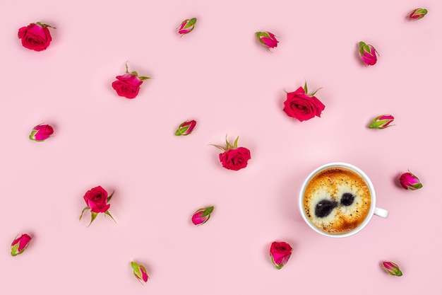 Taza de café y rosas sobre fondo rosa