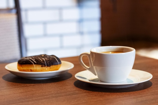 Taza con café y una rosquilla en un plato