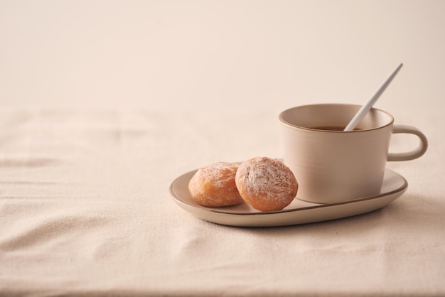 Taza de café con rosquillas para el desayuno sobre fondo claro