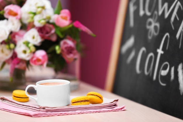 Taza de café, sabroso pastel y hermoso ramo de flores en el café