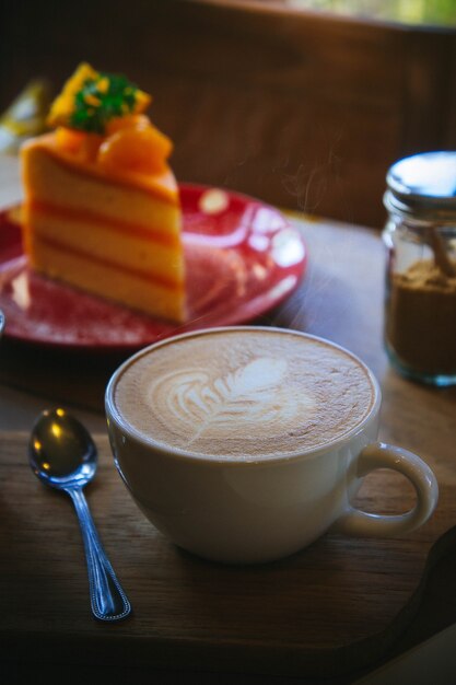 taza de café y sabroso pastel en la mesa de madera y papel en blanco a la espera de ideas