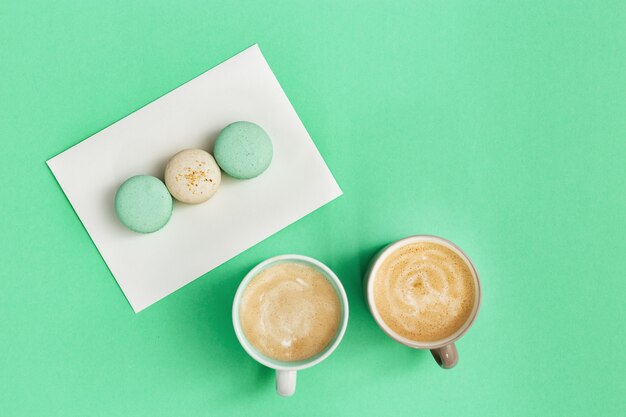 Taza de café y sabrosos macarrones para el desayuno en papel de menta, bebidas calientes por la mañana y dulces