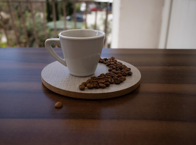 Foto una taza de café se sienta en una mesa de madera con frijoles.