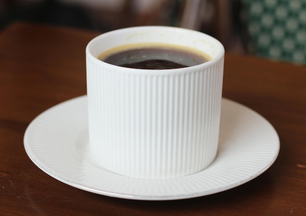 Una taza de café se sienta en el plato en la cafetería