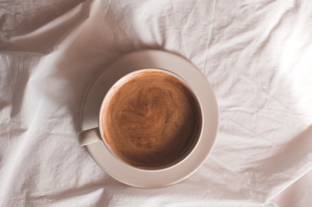 Taza de café sobre fondo blanco en la mesa de cerca. Vista superior. Buenos días. Hora del desayuno.