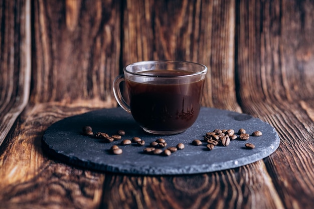 Una taza de café sobre una superficie de piedra con granos de café.