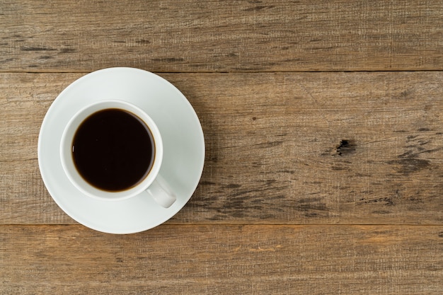 Una taza de café sobre tabla de madera en mal estado.