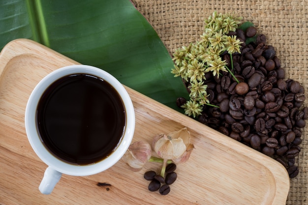 Foto taza de café sólo y granos de café en fondo de madera.