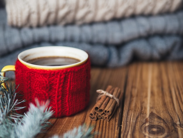 Taza de café con suéter de invierno cálido y copia espacio en la mesa de madera