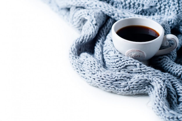 Taza de café y suéter de punto en la mesa blanca