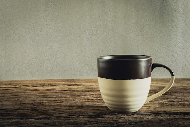 Taza de café en tablero de madera contra la pared del grunge