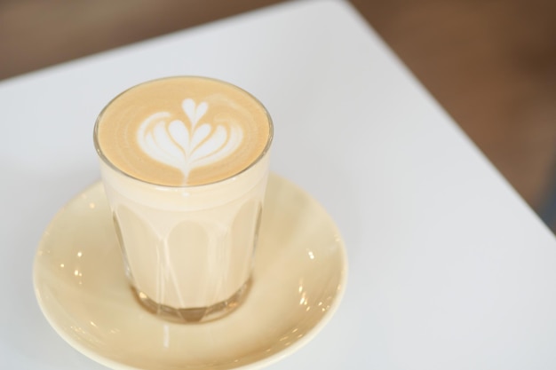 Una taza de café tardío con un diseño en forma de flor en la parte superior del café