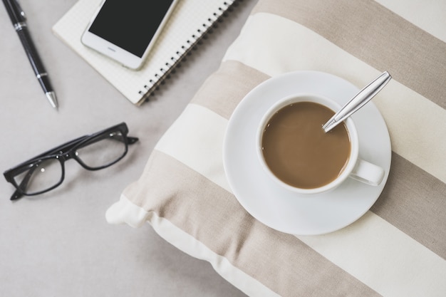 Taza de café con teléfono móvil, gafas y portátil