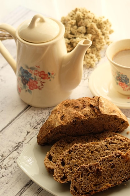 una taza de café, tetera y rebanadas de pan integral de masa fermentada. sobre una mesa de madera. desayuno. sin gluten