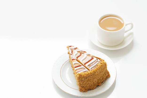 Taza de café y trozo de pastel en la mesa blanca