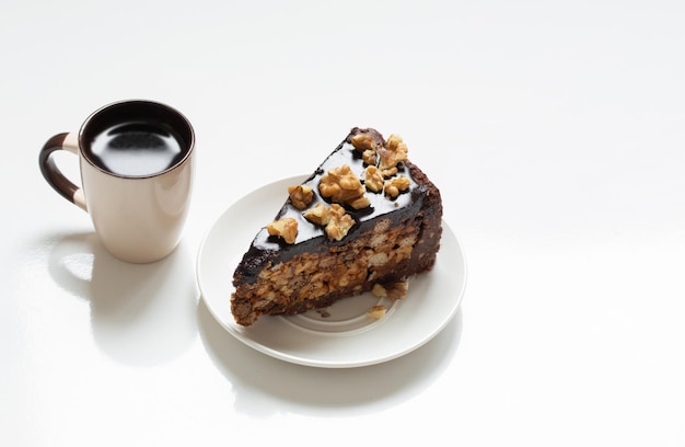 Taza de café y trozo de pastel en la mesa blanca