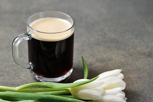 Una taza de cafe y tulipanes blancos