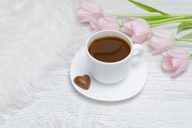 Taza de café y tulipanes rosados.