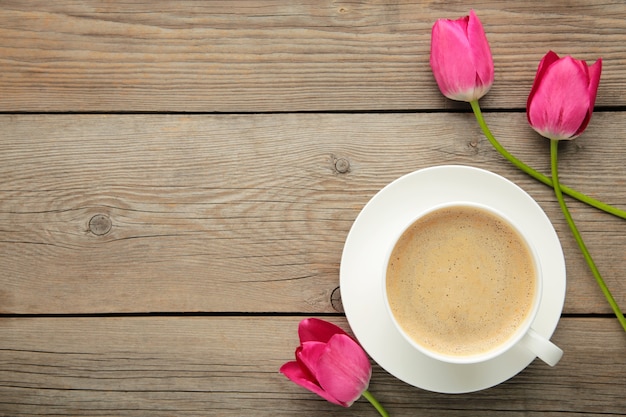 Taza de café con tulipanes rosas sobre superficie gris con espacio de copia