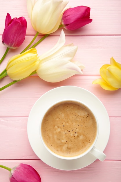 Taza de café con tulipanes en superficie rosa con espacio de copia