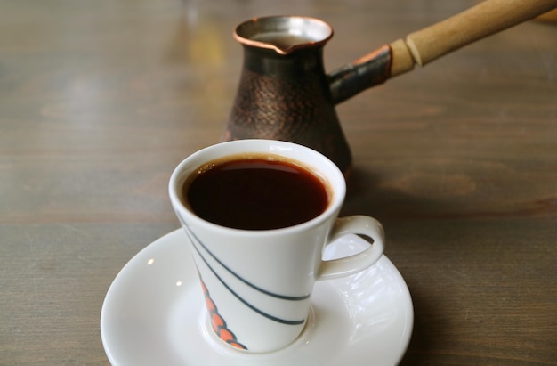 Taza de café turco caliente con caldera de café en la mesa de madera