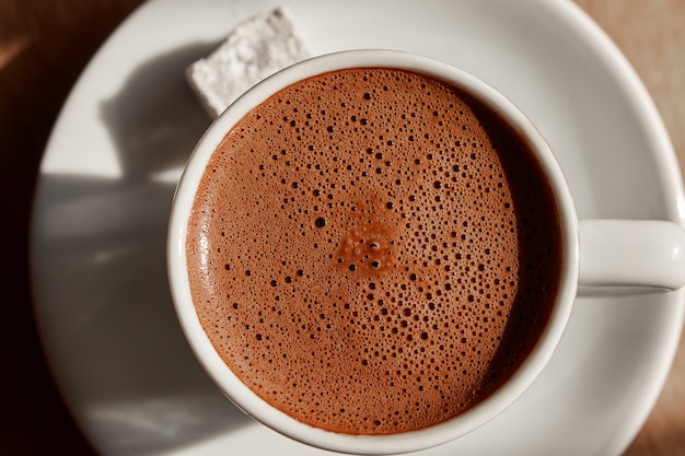 Taza de café turco con espuma sobre una mesa de madera marrón, topview