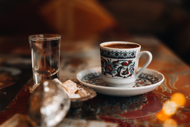 Una taza de café turco tradicional negro fuerte, delicia de dulces y un vaso pequeño de agua. Bebidas tradicionales, conceptos de café.