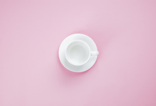 Taza de café vacía sobre un fondo rosa