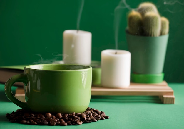 taza de café verde caliente con vapor y frijoles cactus velas apagadas con humo verde oscuro