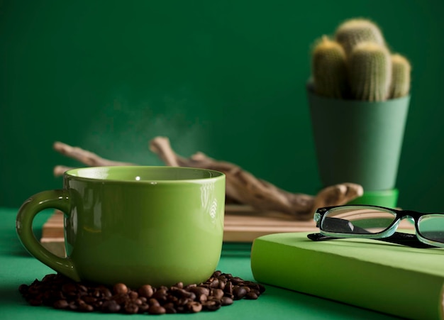 taza de café verde caliente con vapor viejo tronco de madera cactus libro y gafas de lectura texto espacial